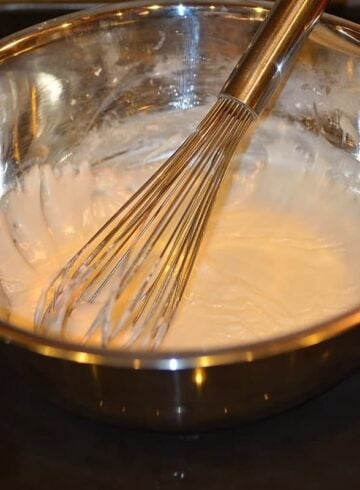 powdered sugar, milk, and lemon juice being whisked in a metal bowl