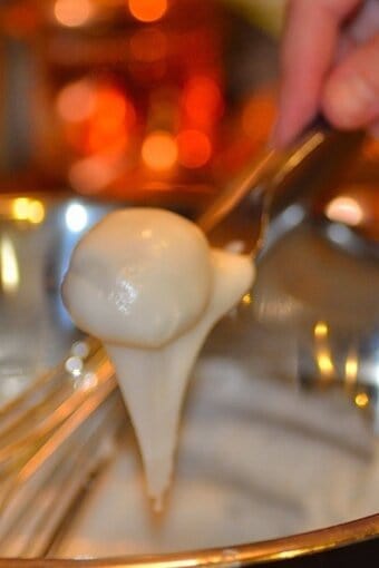 camaféu de nozes being dipped in the fondant glaze with a fork