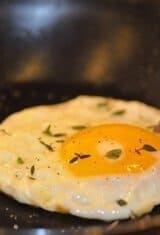 sunny side up egg almost cooked in a pan -- without a ring