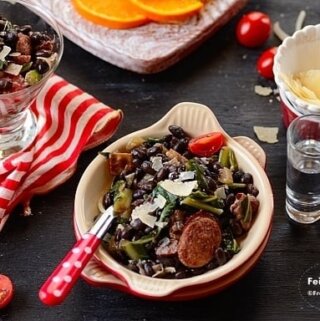 A bowl of salad with sausage and beans