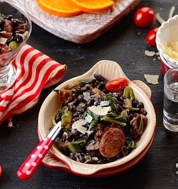 A bowl of salad with sausage and beans