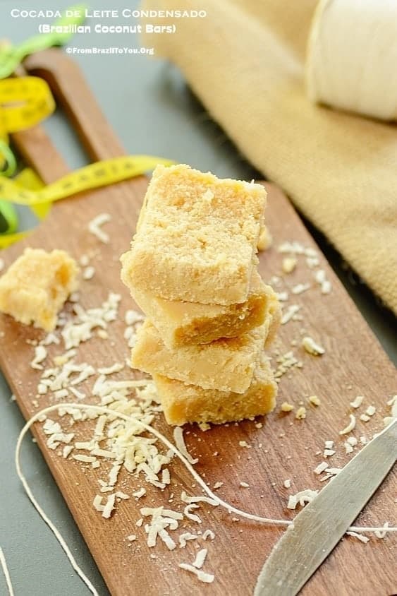 Stack of cocada de Leite condensado or sweet coconut bars on a wooden cutting board