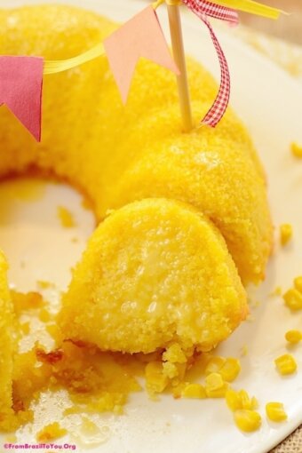 A slice of corn cake close to the rest of the cake decorated with a flag bunting on top