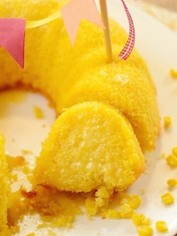 A slice of corn cake close to the rest of the cake decorated with a flag bunting on top