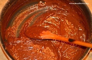 chocolate fudge mixture being stirred in a pan with a wooden spoon