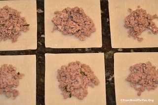 wonton skin squares with beef filling on top, which will be sealed to make empanadas