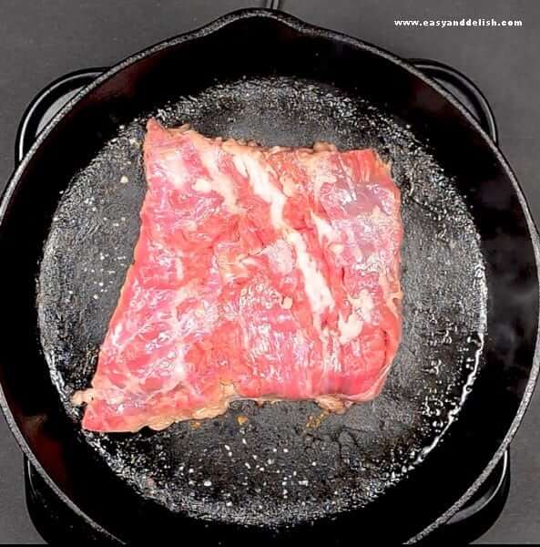 searing skirt steak in a pan