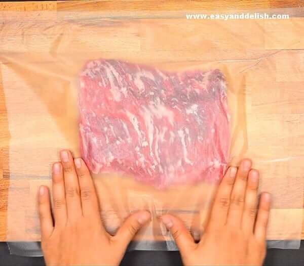 skirt steak covered with a plastic to pound the meat