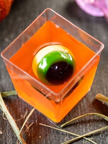Jello cups with orange gelatin and a creepy gummy eyeball.
