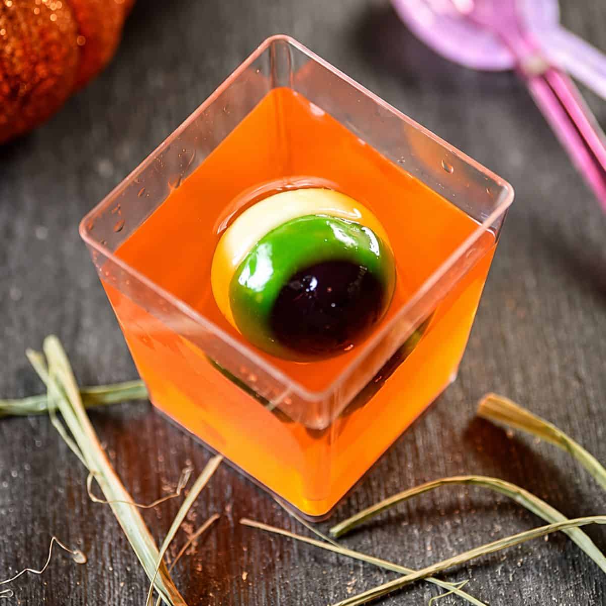 Jello cups with orange gelatin and a creepy gummy eyeball.