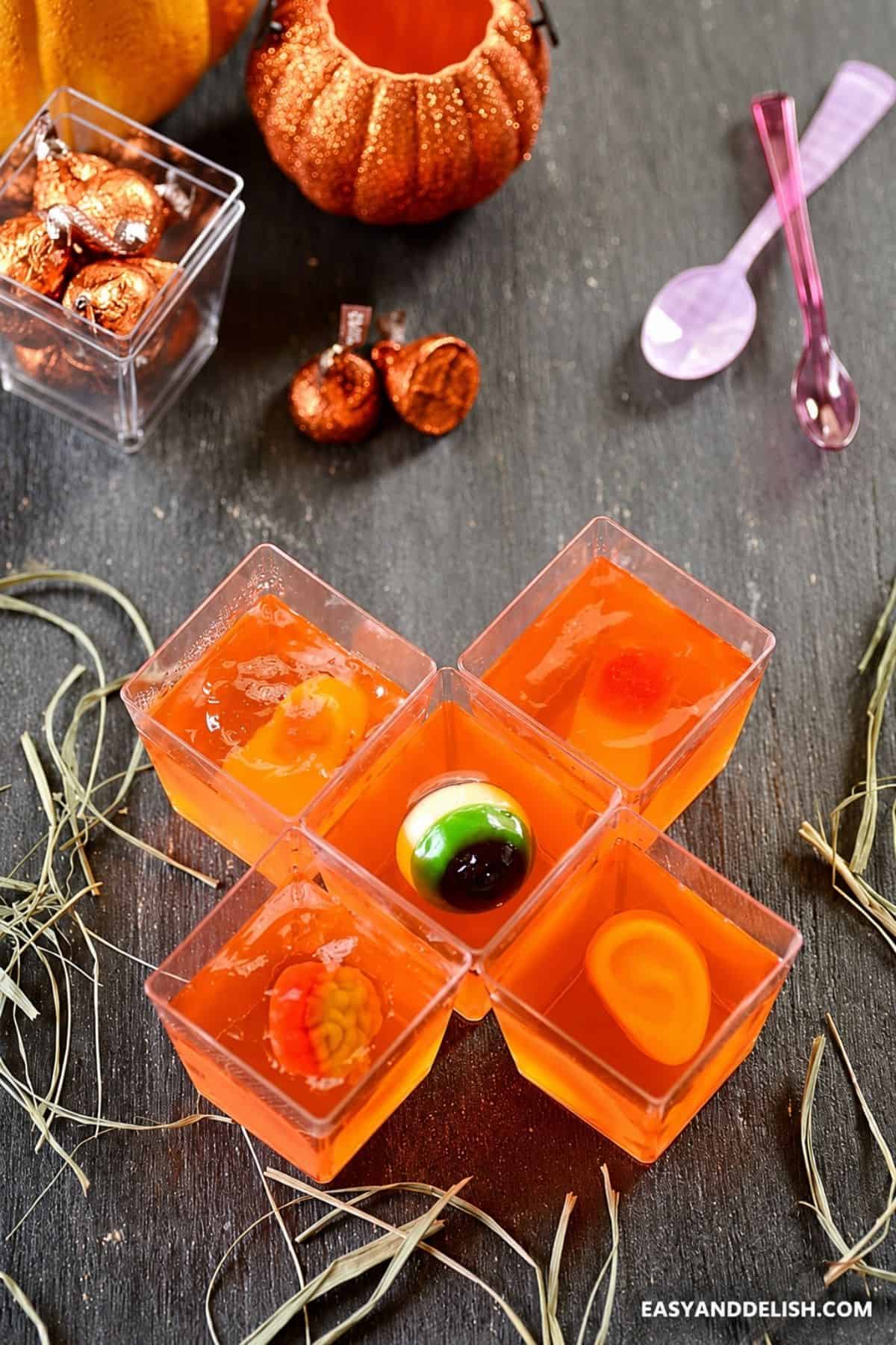 Orange gelatin cups topped with assorted creepy gummy candies.