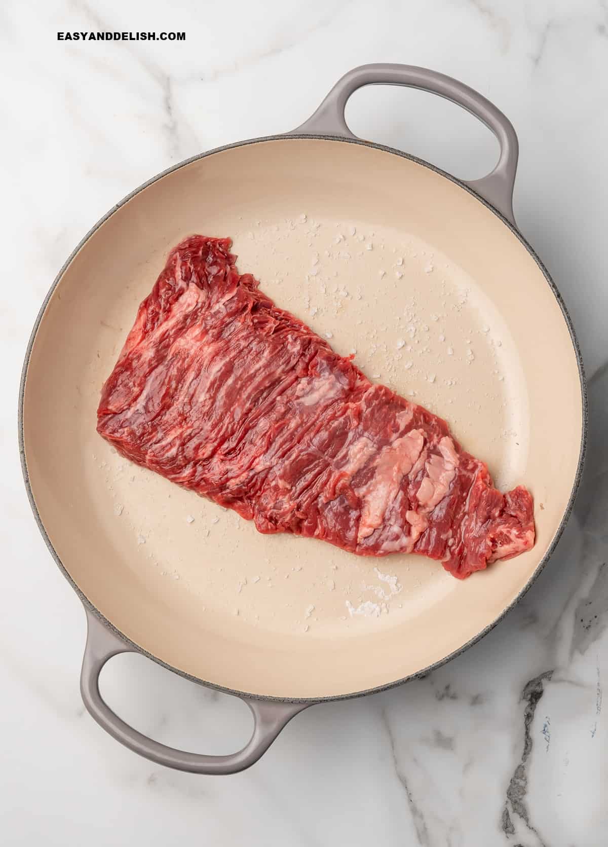 skirt steak in a pan over coarse salt