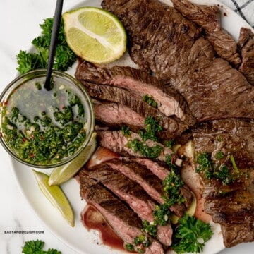 skirt steak with chimichurri sauce and lime wedges in a plate.