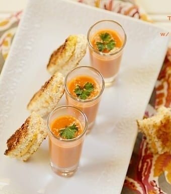 Three glasses of tomato soup with bread slices