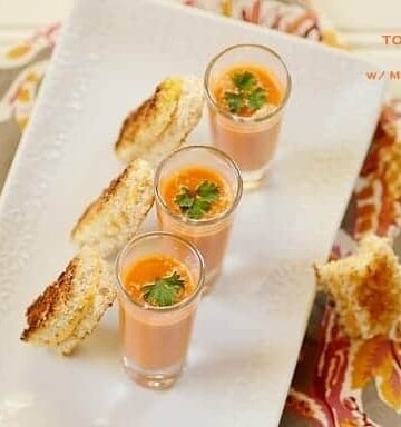 Three glasses of tomato soup with bread slices