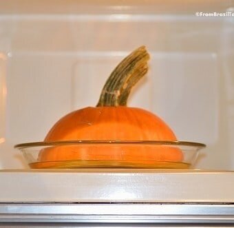 pumpkin half cooking on a glass plate in the microwave