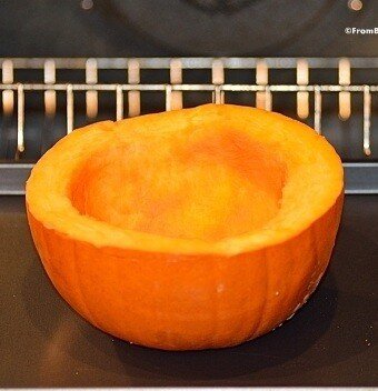 pumpkin half resting on baking sheet for cooking in the oven