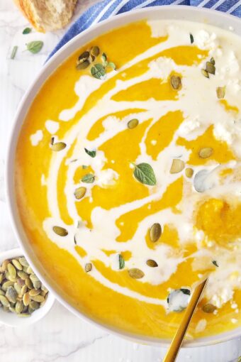 close up of a bowl of vegan pumpkin soup drizzled with coconut milk