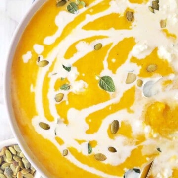 close up of a bowl of vegan pumpkin soup drizzled with coconut milk