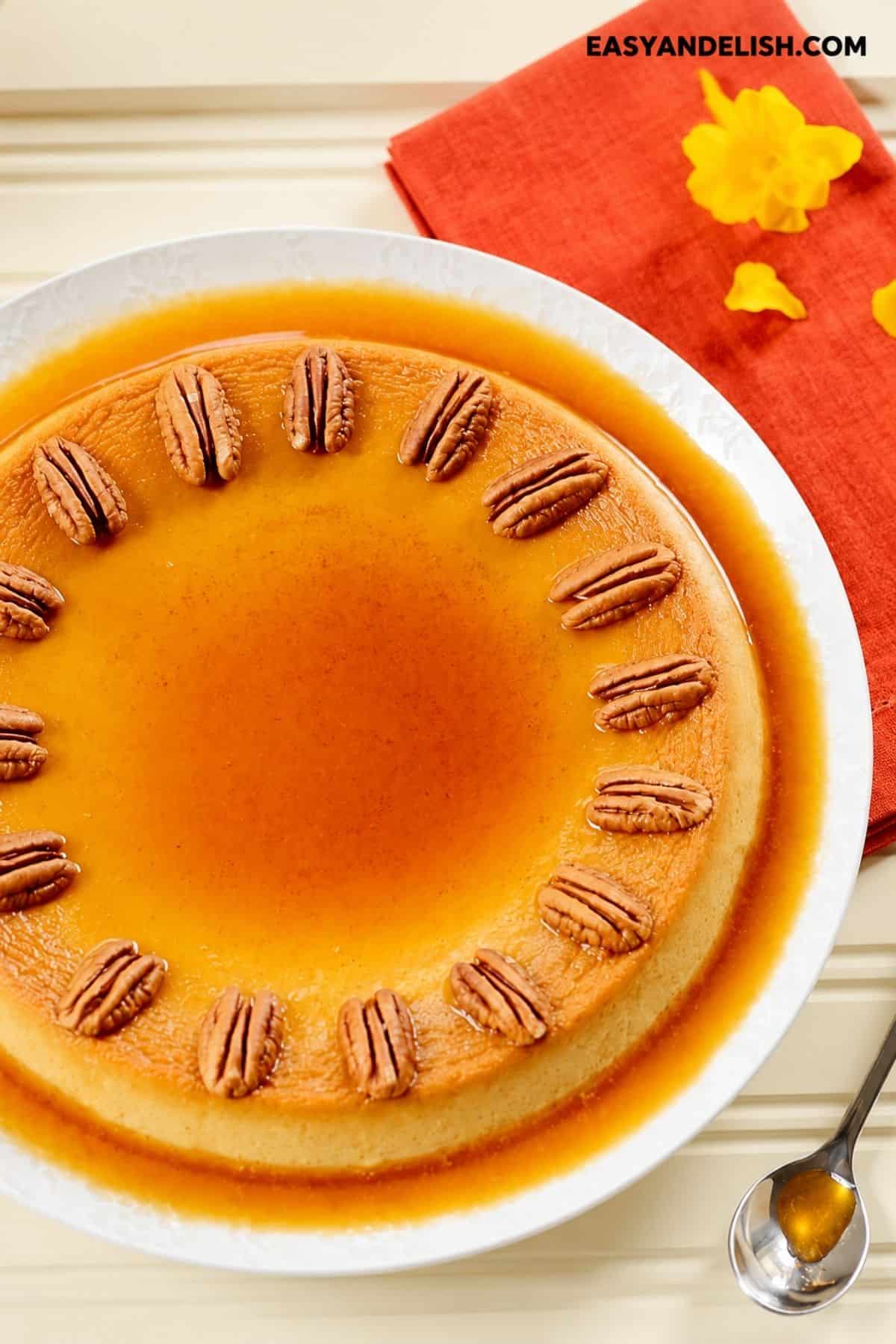 Whole pumpkin flan topped with roasted pecans and surrounded by caramel sauce.