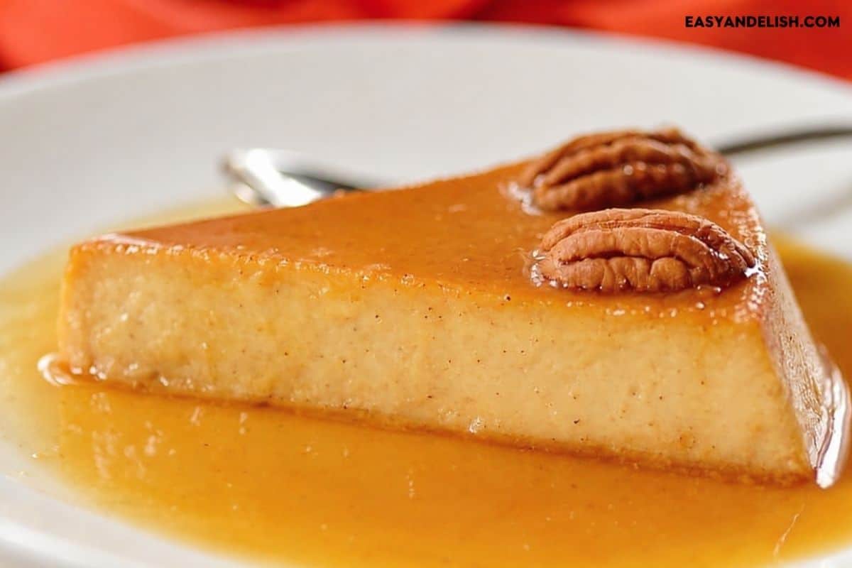Slice of pumpkin pie flan topped with pecans and caramel sauce.