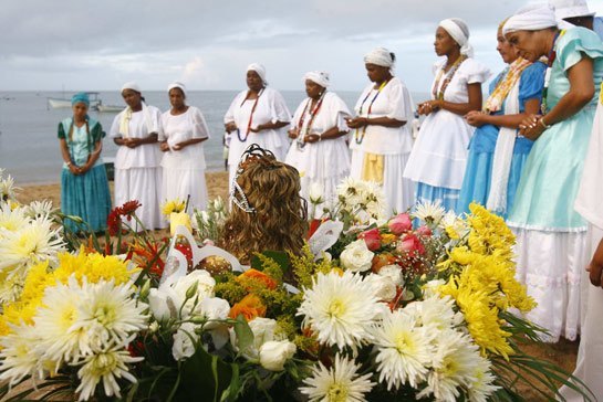 A group of people in white attire standing in row and surrounded by flowers
