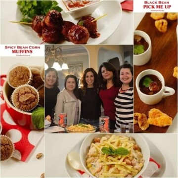 A bunch of different types of food on a table plus people standing in the center