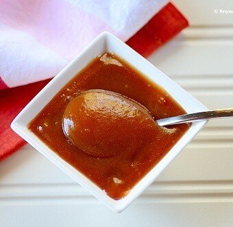 metal spoon dipping into a square white bowl of melted guava paste