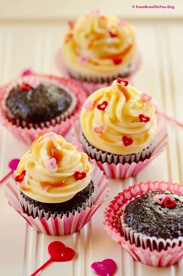 Valentine's day cupcakes filled with guava paste and topped with cream cheese frostinga dn sprinkles on a tray.