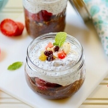 Breakfast in a jar sitting on top of a table with sliced strawberries