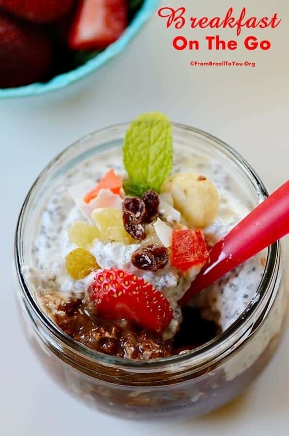 Breakfast in a jar sitting on top of a table with sliced strawberries