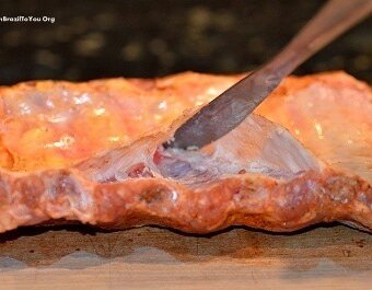 A dull butter knife is slipped beneath the membrane of the baby back ribs