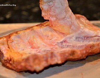 The loosened white membrane is stripped off the rack of baby back ribs by hand