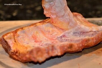 The loosened white membrane is stripped off the rack of baby back ribs by hand