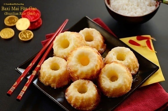 Several round sticky rice cakes on a black square plate with red chopsticks