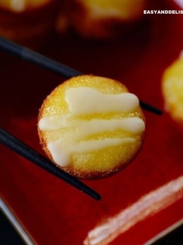 close up of sweet rice cake between chopsticks.