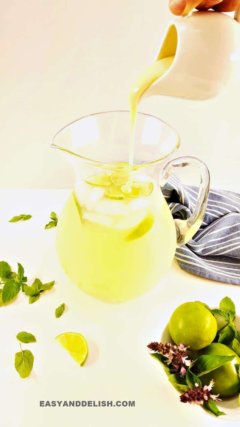 pouring condensed milk into a pitcher with lemonade