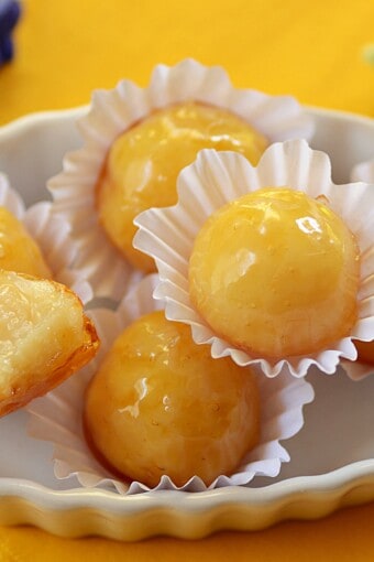 coconut bonbons with hard caramel shell in a tray. Most are whole and one is halved