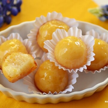 coconut bonbons with hard caramel shell in a tray. Most are whole and one is halved