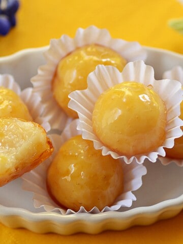 coconut bonbons with hard caramel shell in a tray. Most are whole and one is halved