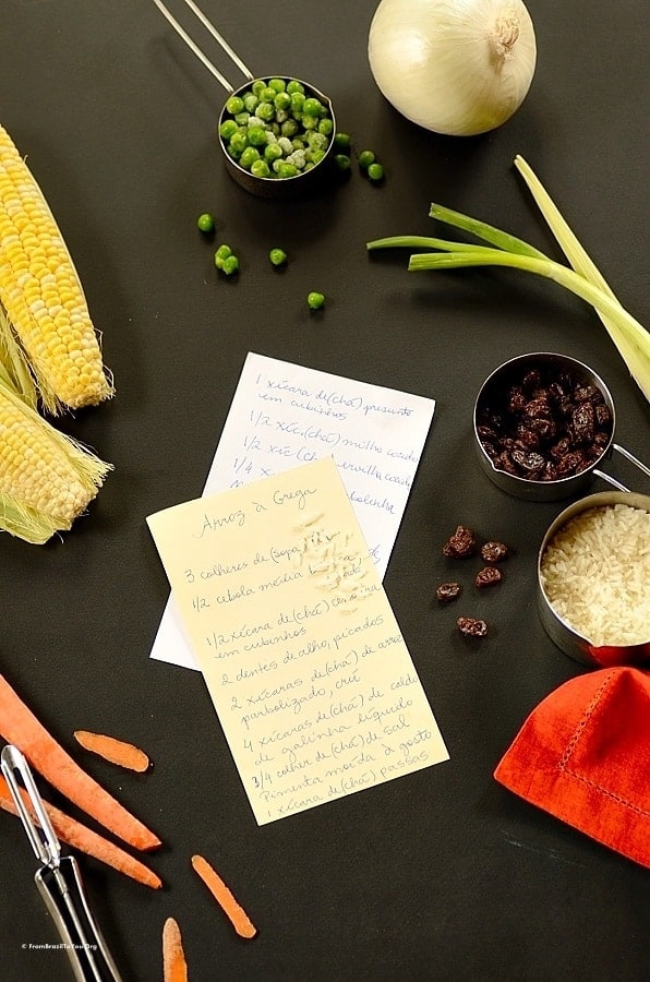 Ingredients to make Greek rice sitting on a black table with written recipe papers