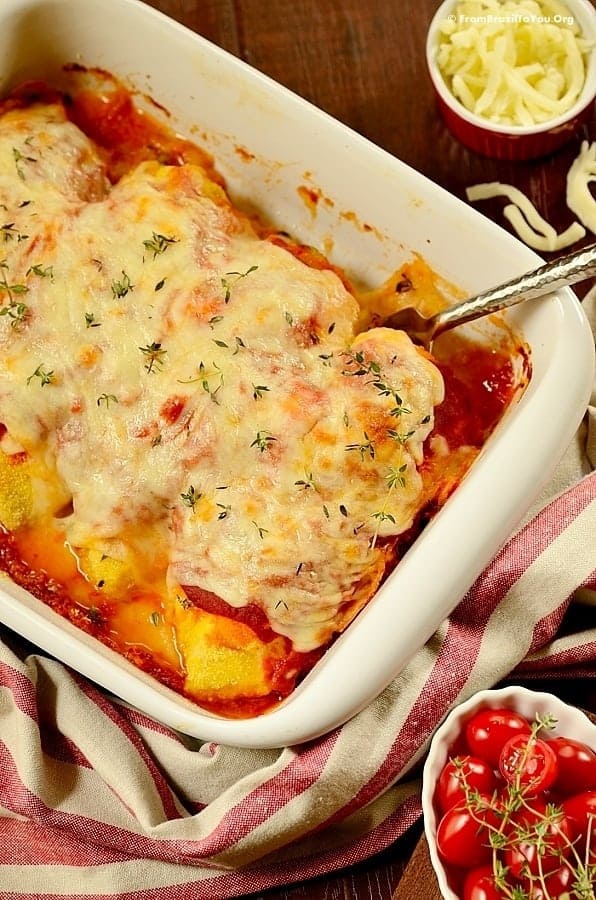 close up of baked chicken parmesan in baking dish with garnishes around