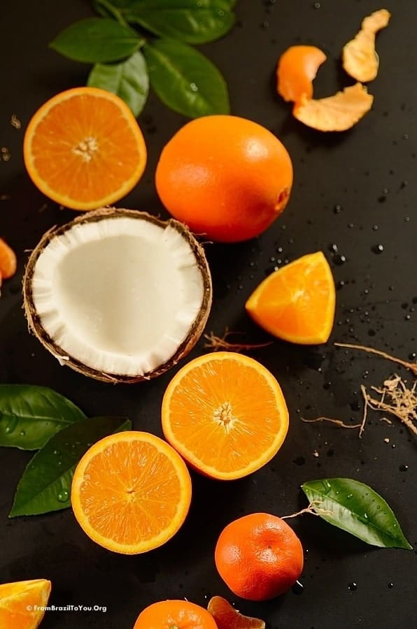 Sliced oranges and a cracked coconut shell on a black board