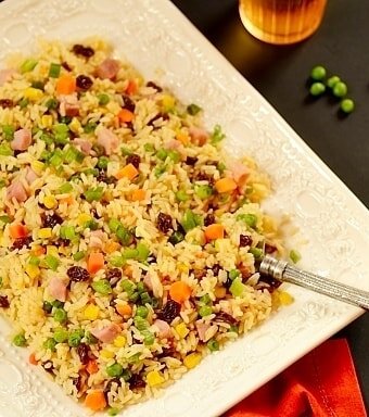 Greek rice or arroz a grega served on a white dish with a fork and red napkin