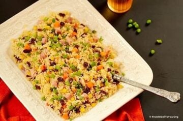 Greek rice or arroz a grega served on a white dish with a fork and red napkin