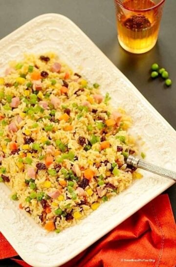 Greek rice or arroz a grega served on a white dish with a fork and red napkin