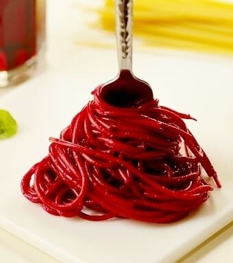 pasta colored red with beet juice being twirled on a fork