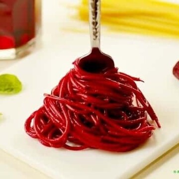 pasta colored red with beet juice being twirled on a fork
