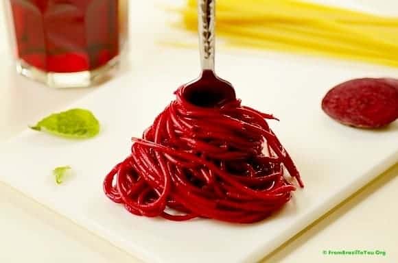 pasta colored red with beet juice being twirled on a fork