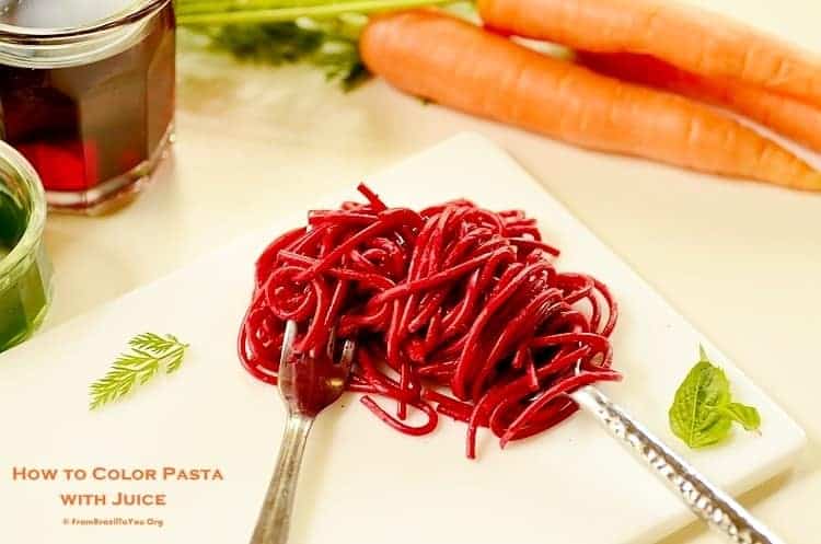 pasta co,lored with beet juice over a platter with silverware plus other veggies for how to color pasta with juices